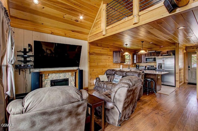 living area featuring lofted ceiling, wooden walls, a fireplace, wood finished floors, and wood ceiling