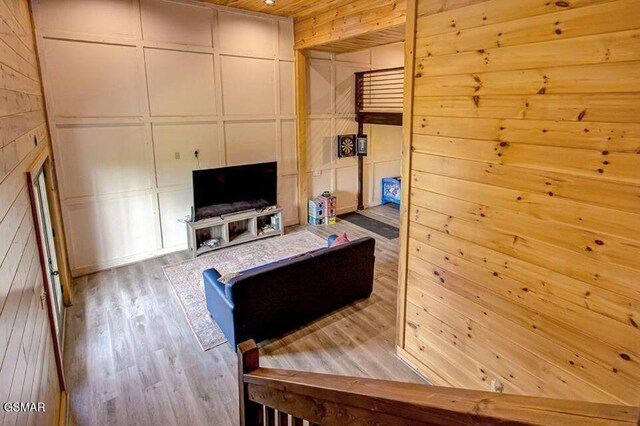 living room featuring a decorative wall, wooden walls, and wood finished floors