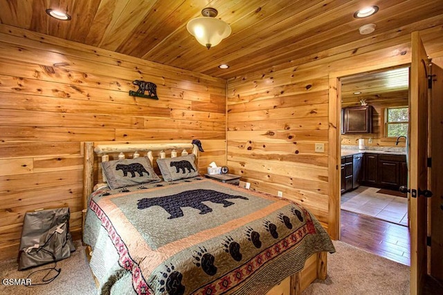 bedroom with wood ceiling, connected bathroom, and wooden walls