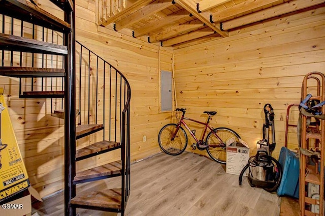 interior space featuring electric panel, wooden walls, and wood finished floors