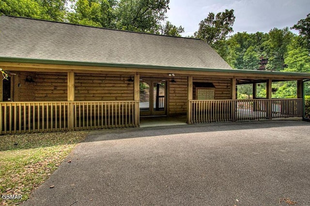 log-style house featuring a shingled roof and driveway