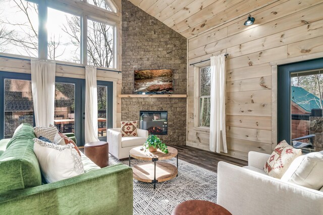 living room with a stone fireplace, hardwood / wood-style floors, wooden ceiling, wooden walls, and vaulted ceiling