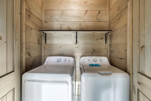 washroom with washer and clothes dryer and wooden walls