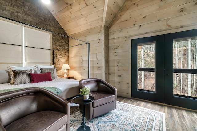 bedroom featuring french doors, wood walls, light hardwood / wood-style flooring, and lofted ceiling