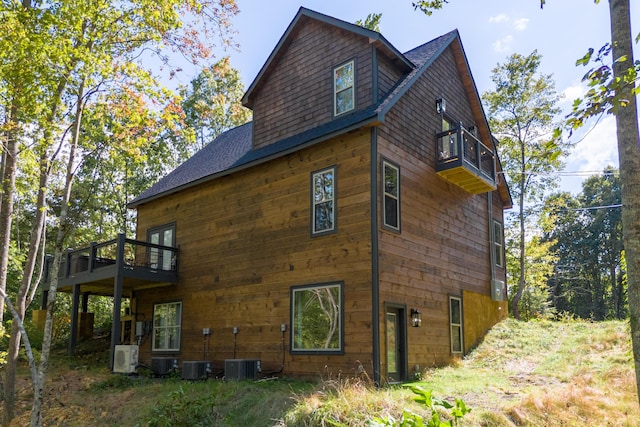 view of side of property with a balcony, ac unit, and central AC