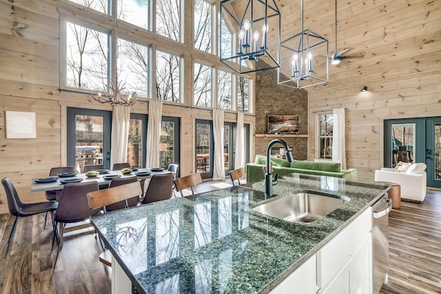 kitchen featuring hanging light fixtures, white cabinets, a kitchen island with sink, and a towering ceiling