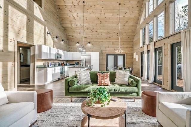 living room with french doors, high vaulted ceiling, light hardwood / wood-style flooring, and wooden walls