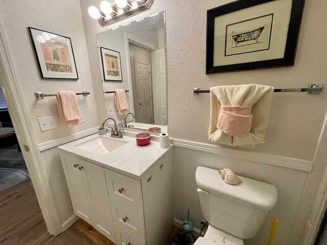 4955 Ledford Rd, Cosby, TN 37722 - bathroom with a textured wall, toilet, a wainscoted wall, wood finished floors, and vanity
