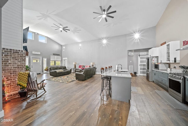 kitchen with light stone countertops, appliances with stainless steel finishes, a breakfast bar, sink, and white cabinets