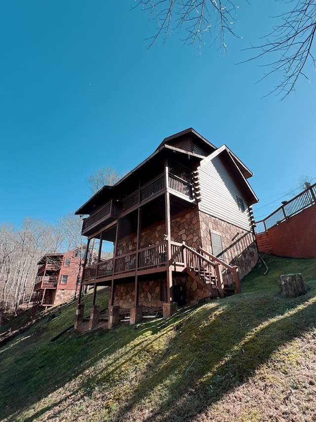 rear view of house featuring a balcony, a yard, and a wooden deck