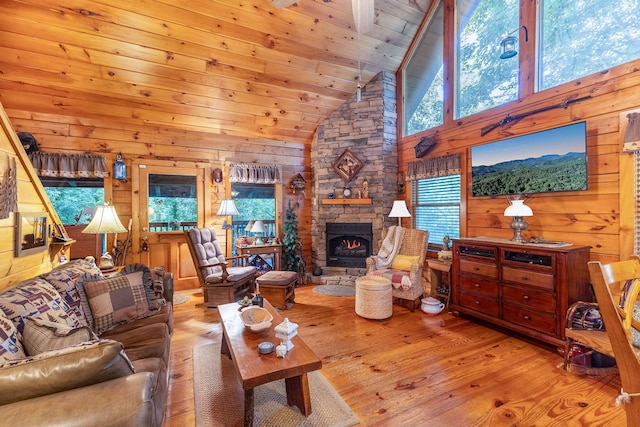 living room featuring a stone fireplace, wooden walls, hardwood / wood-style floors, and high vaulted ceiling