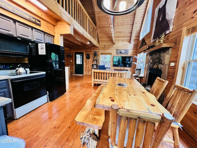 2527 Raccoon Hollow Way, Sevierville, TN 37862 - dining room with wooden walls, a wood ceiling with exposed beams, light wood-style floors, high vaulted ceiling, and a fireplace