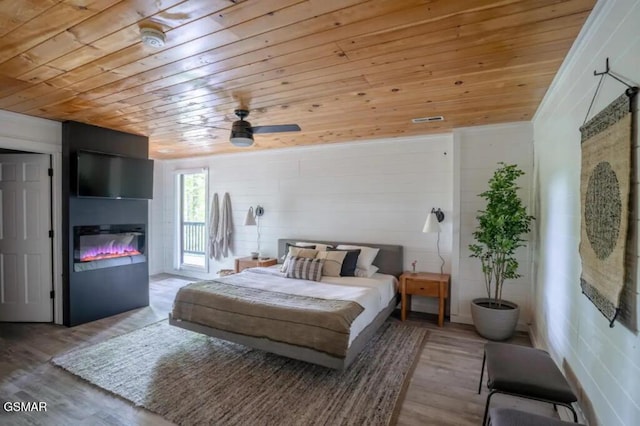 bedroom with wood ceiling, access to outside, ceiling fan, hardwood / wood-style flooring, and a fireplace