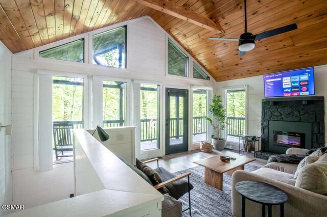 sunroom with a fireplace, lofted ceiling with beams, ceiling fan, and wooden ceiling