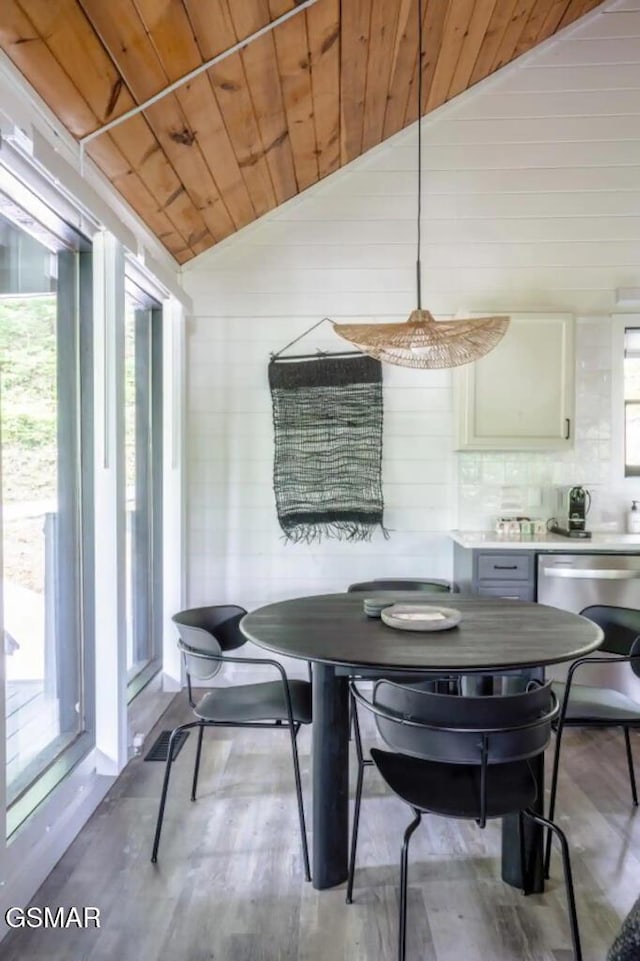 dining area with light hardwood / wood-style flooring, vaulted ceiling, plenty of natural light, and wood ceiling