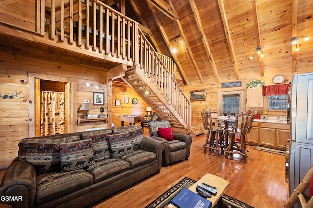 living room with high vaulted ceiling, wood walls, beam ceiling, wooden ceiling, and light wood-type flooring