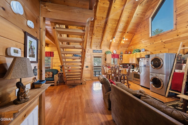 living room featuring beam ceiling, light wood-type flooring, wooden ceiling, wooden walls, and stacked washing maching and dryer