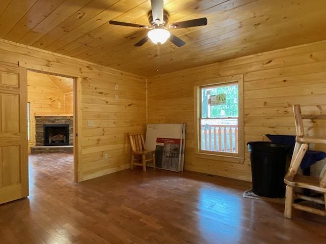 unfurnished living room featuring wood finished floors, a fireplace, ceiling fan, wooden walls, and wood ceiling