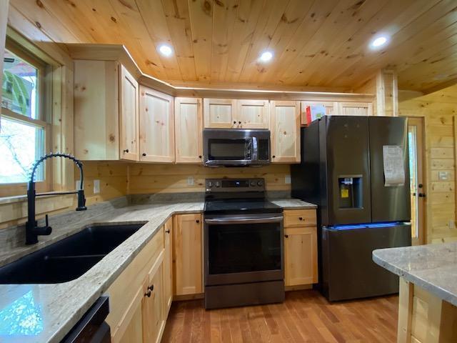 kitchen featuring light stone counters, sink, black appliances, and wooden ceiling