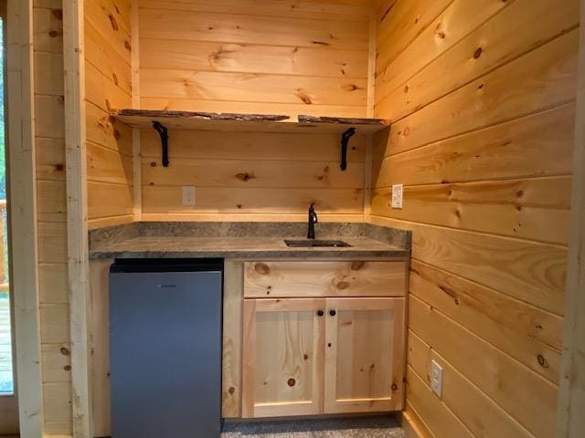 bar with refrigerator, wood walls, and a sink