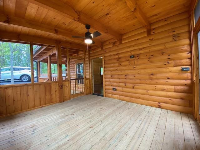 unfurnished sunroom with beamed ceiling, ceiling fan, and wood ceiling