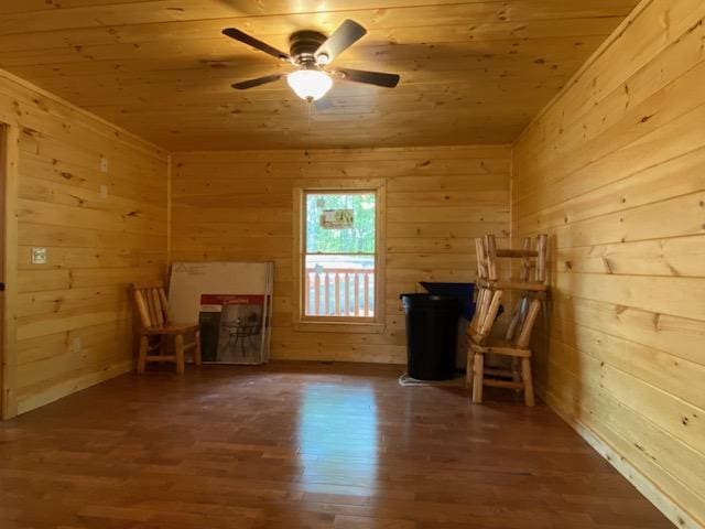 interior space with wood walls, wood ceiling, a ceiling fan, and wood finished floors