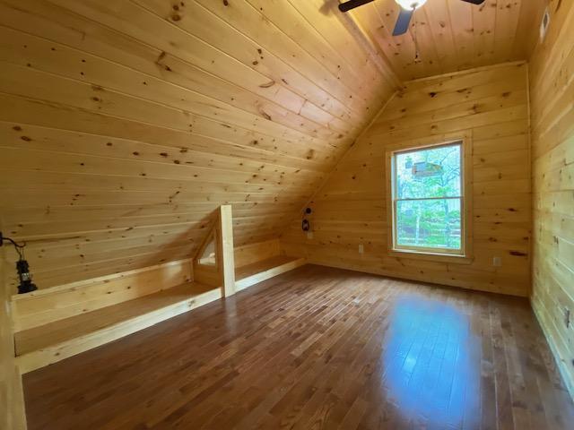 bonus room featuring wood ceiling, ceiling fan, hardwood / wood-style flooring, lofted ceiling, and wood walls