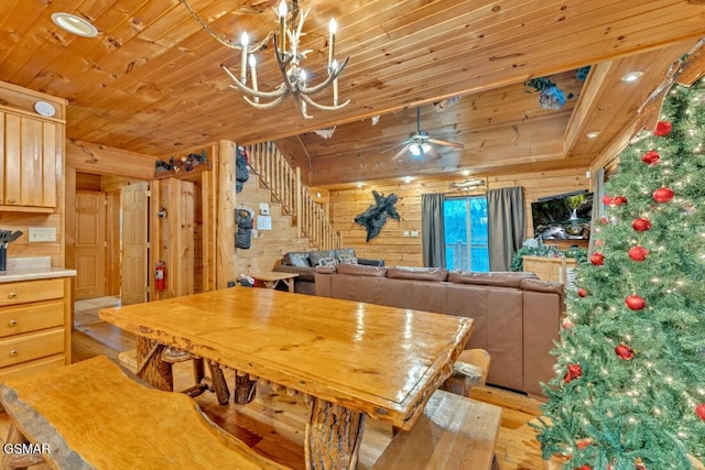 dining room featuring ceiling fan with notable chandelier, light hardwood / wood-style floors, wooden ceiling, and wood walls