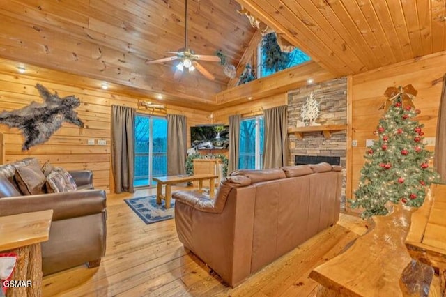 living room featuring a stone fireplace, ceiling fan, wooden ceiling, and light wood-type flooring