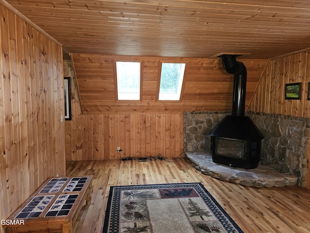 interior space with hardwood / wood-style flooring, a wood stove, wooden ceiling, and wood walls