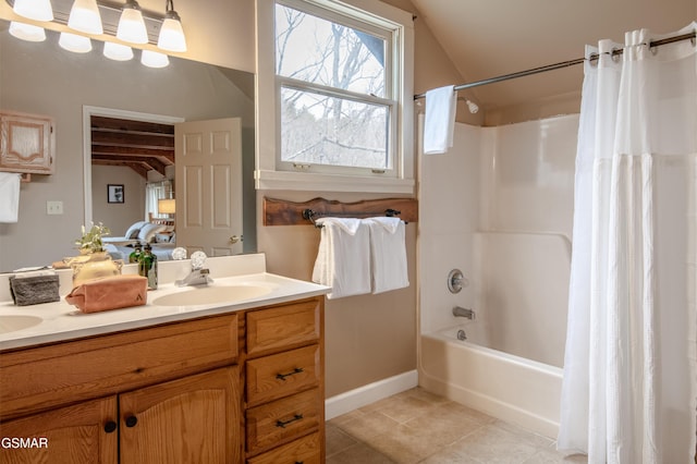 full bath with double vanity, shower / bath combo with shower curtain, a sink, baseboards, and tile patterned floors