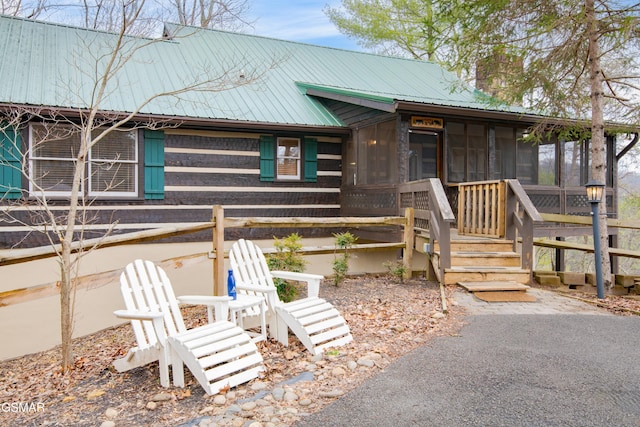 chalet / cabin featuring metal roof, a chimney, and a sunroom