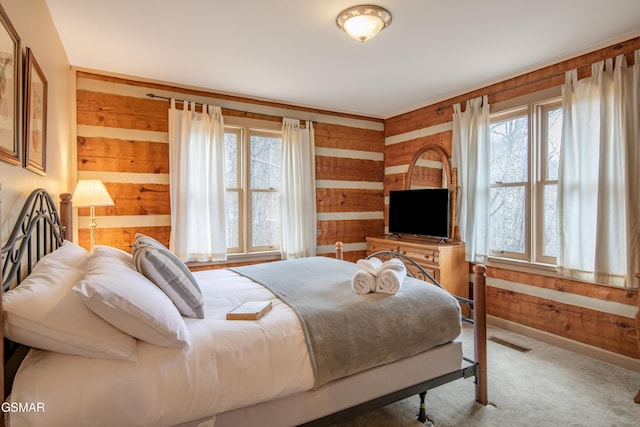 bedroom featuring wood walls, carpet flooring, visible vents, and baseboards