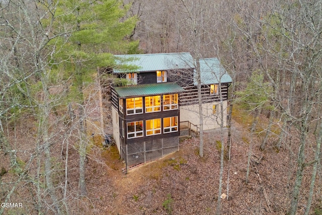 rear view of property with metal roof and a wooded view