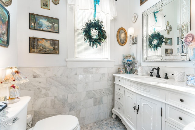 bathroom featuring tile patterned floors, vanity, toilet, and tile walls