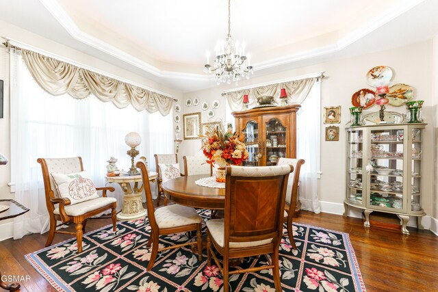 dining space featuring a raised ceiling, a chandelier, and dark hardwood / wood-style floors