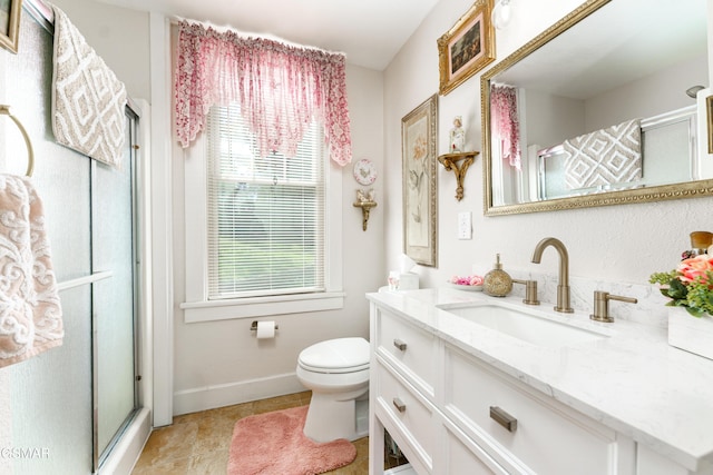 bathroom featuring vanity, toilet, plenty of natural light, and a shower with shower door