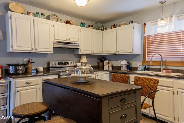 kitchen with a center island, stainless steel appliances, dark countertops, a sink, and under cabinet range hood