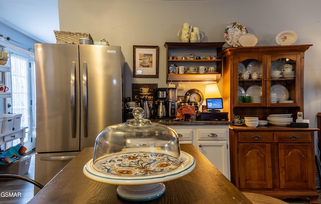 kitchen with glass insert cabinets, freestanding refrigerator, white cabinets, and dark countertops