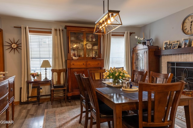 dining room featuring a brick fireplace and wood finished floors