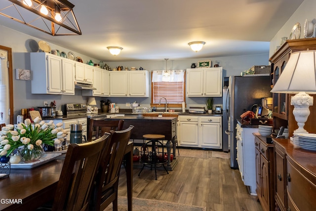 kitchen with under cabinet range hood, white cabinetry, electric stove, dark countertops, and dark wood finished floors