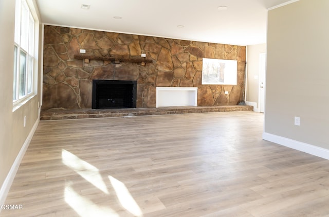 unfurnished living room featuring a stone fireplace and light wood-type flooring