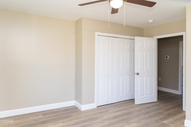 unfurnished bedroom featuring ceiling fan, a closet, and light wood-type flooring