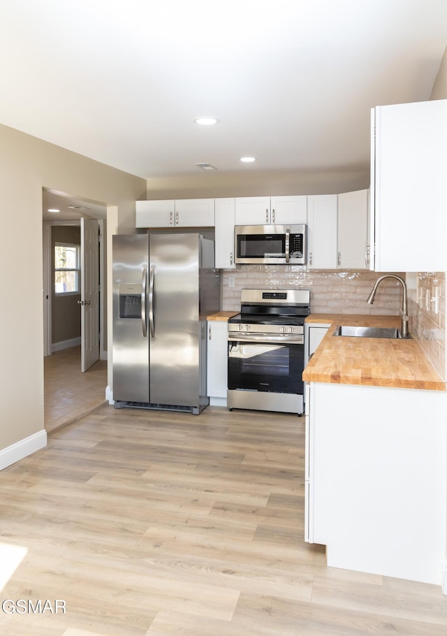 kitchen featuring wood counters, sink, stainless steel appliances, decorative backsplash, and white cabinets