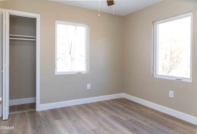 unfurnished bedroom with multiple windows, light hardwood / wood-style floors, ceiling fan, and a closet