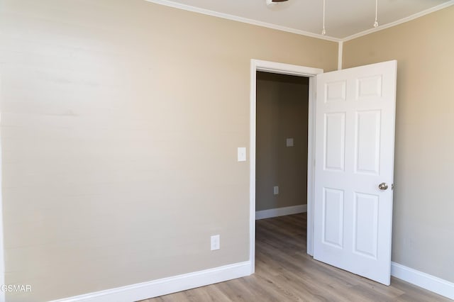 empty room with ornamental molding and light hardwood / wood-style flooring