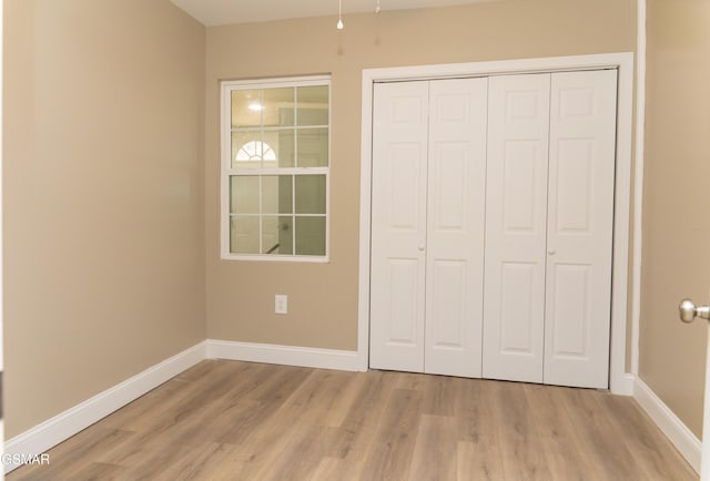 unfurnished bedroom featuring a closet and light wood-type flooring