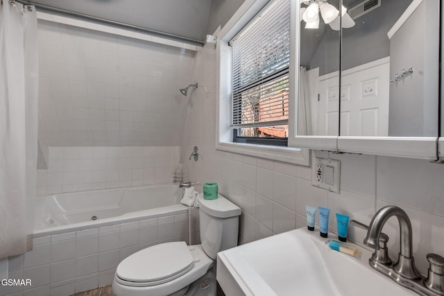 full bathroom featuring sink, shower / tub combo, tile walls, decorative backsplash, and toilet