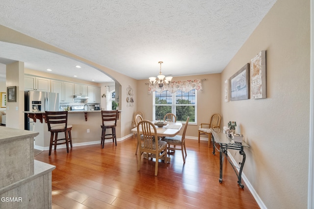 854 River Cliff Dr, Kodak, TN 37764 - dining area featuring arched walkways, a chandelier, light wood-style floors, a textured ceiling, and baseboards