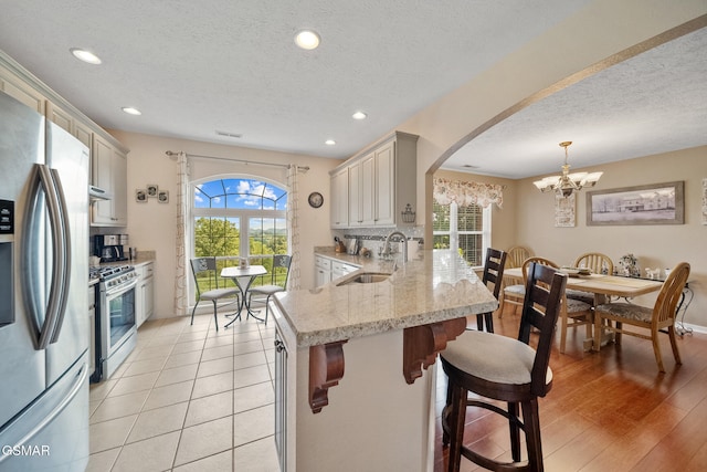 854 River Cliff Dr, Kodak, TN 37764 - kitchen featuring stainless steel appliances, a sink, a chandelier, arched walkways, and a textured ceiling